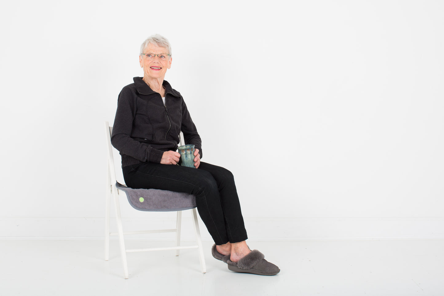 Elderly woman sitting on the chair covered with waterproof grey PeapodMat. 100% leakproof.